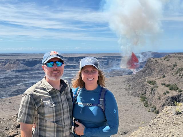 Jason and Kat standing in front of an erupting volcano.